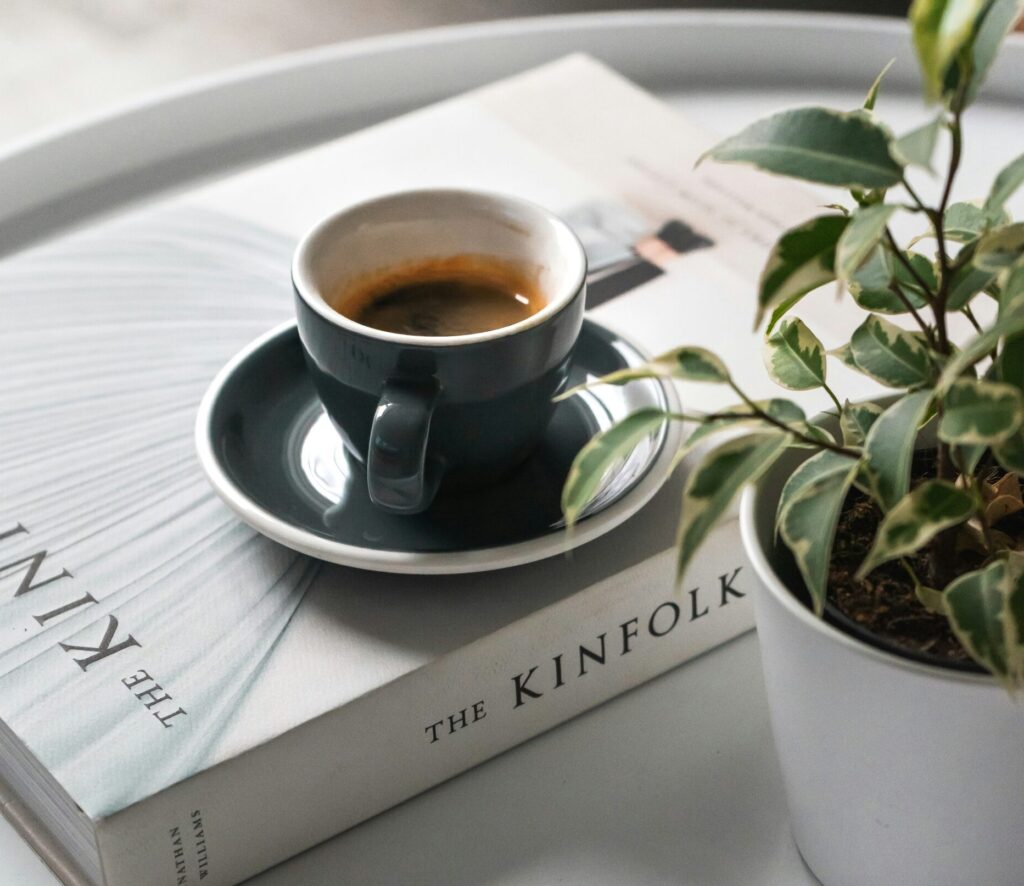 Café em cima de um livro, com uma planta ao lado. Como recuperar o hábito da leitura?